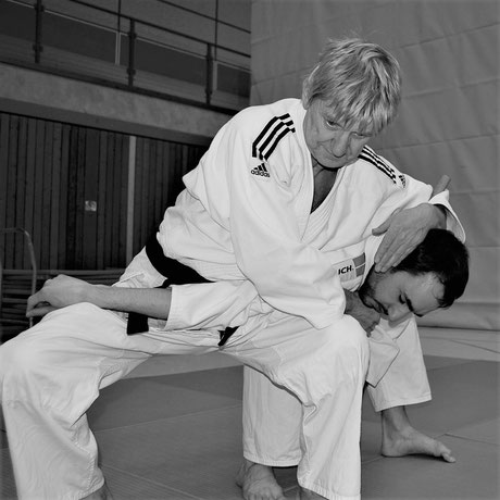 Der Jiu Jitsu Sensei zeigt eine Festlegetechnik an einem Schüler gegen einen Stockangriff.