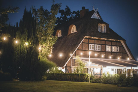 Fachwerkhaus im Abendlicht, die Terrasse ist beleuchtet
