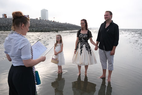 Constanze Marienfeld bei einer Freien Trauung in Büsum, mitten im Watt, das Brautpaar, das Blumenmädchen und die Rednerin stehen bis zum Knöchel im Wasser, während Constanze sie traut