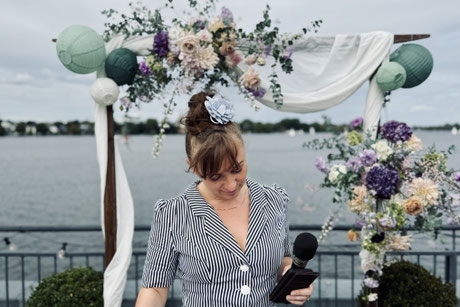 Constanze Marienfeld geht ein letztes Mal die Rede durch, sie steht vor einem reich geschmückten Traubogen auf der Terrasse an der Alster