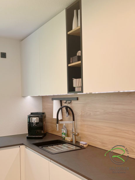 Kompakte, weiß u. Anthrazite Stauraumküche, grifflose Hängeschränke mit integrierter LED Arbeitsplatzbeleuchtung, heller Holzdekor Nischenplatte, großem, anthrazitem Spülbecken, Edelstahl Schlauchbrause Soneo Flex, schwarzem Relingsystem für Papiertuch