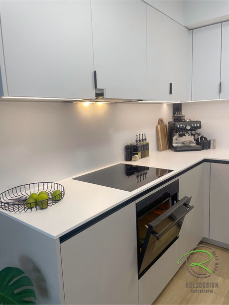 Kleine Einbauküche über Eck mit weißer 12 mm Kompakt Arbeitsplatte mit flächenbündig eingebautes Induktionskochfeld