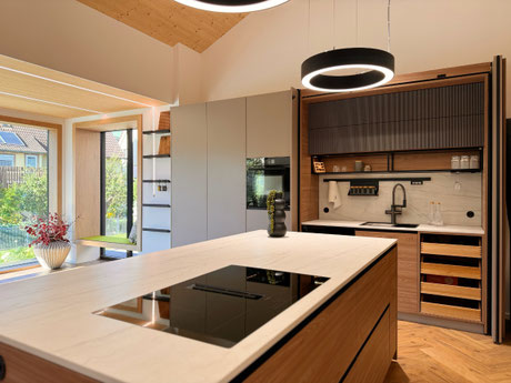 Küche nach Maß mit Kochinsel und Pocket-Door-Schrank in steingrau und Ulmendekor mit Riffelfronten, offenem schwarzen Stahlregal – geplant und gefertigt von Holzdesign Ralf Rapp in Geisingen
