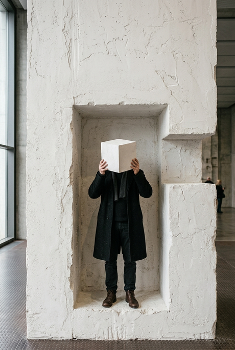 Mann versteckt sich hinter Gipswürfel in Ausstellung
