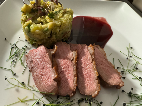 aufgeschnitten rosa Entenbrustscheiben auf weissem Teller an einer dunkelroten Glühweinsauce und einem Rosenkohl-Walnuss-Kartoffelstampf, dekoriert mit Sprossen