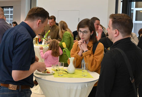 Zwei Männer und eine Frau im Gespräch bei Snacks und Getränken