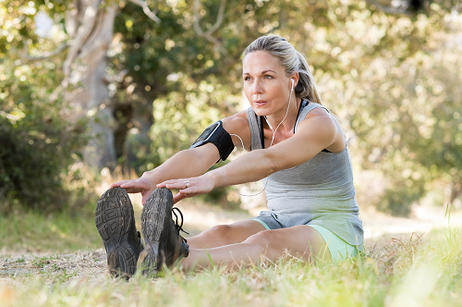 Eine sportliche Frau dehnt sich nach dem Joggen. Hypnose hat geholfen, die Motivation hochzuhalten.