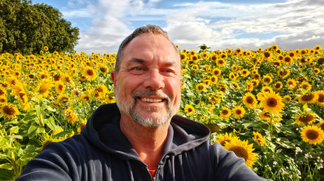 Frédéric Catoul, de L'Abeille Noire, pose devant un champs de fleurs de tournesol.