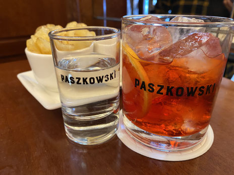 bicchiere di Negroni, bicchierino d'acqua e patatine