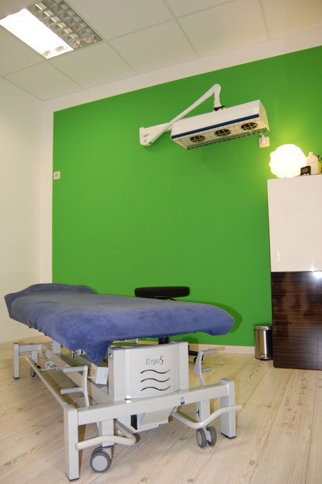 Behandlungsraum mit grüner Akzentwand und Therapieliege in der Physiotherapiepraxis Ralf Zichel