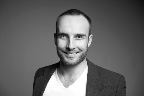 Der Autor Paul Garbulski trägt ein Sakko und lacht in die Kamera.