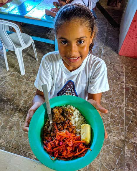 Ein Mädchen zeigt ihren Teller mit Essen