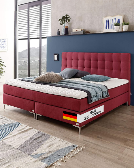 Ein rotes Boxspringbett setzt im Schlafzimmer ein stilvolles Statement, vereint Komfort mit modernem Design und sorgt für eine warme, einladende Atmosphäre.
