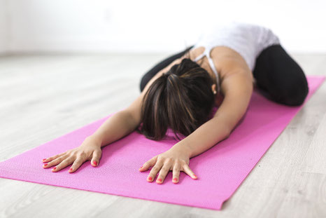 Yogini auf der Yogamatte in Childs Pose / Balasana