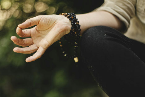 Offene Hand mit Mala im Sonnenschein – Meditation mit Mantra als libevoller Anker im Alltag
