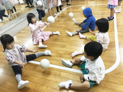 リトミックで、幼稚園児が二人組になって、ピアノに合わせたボール活動を行っています。