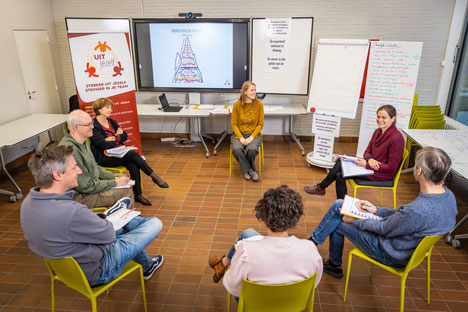 Zes deelnemers en trainster Lieve Vander Linden zitten in een cirkel