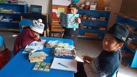 Kinder mit Büchern und Schreibmaterial sitzen um einen Tisch