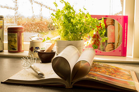 libro di cucina aperto con alcune pagine ripiegate su sé stesse a dare forma di cuore