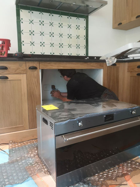 Thierr BESANCON, électricien qualifié, entrain de brancher un four électrique lors de la rénovation d'une cuisine