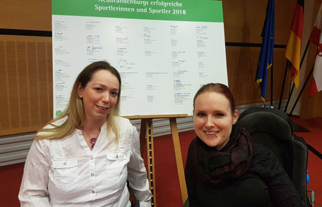 Nicole und Annika vor der Tafel der geehrten Sportler*innen