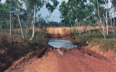 Wasserloch auf der unebenen Fahrbahn