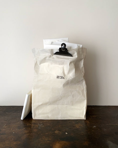 Grocery Bag 23L White｜グロサリーバッグ 23L ホワイト　海外のスーパーマーケットの紙袋のようなデザインのバッグ。アイボリー色の生地に黒いのスタンプマーク。ギザギザにカットされた縁や、紙の折れ跡のようなシワがあり、本物の紙袋のようです。ワックスドコットンという、パラフィンなどを塗布した綿布で作られています。様々なモノを隠して収納する袋として使うと良さそうです。