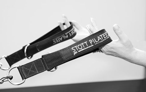 Hands holding Reformer Straps with health wrist and hand alignment using STOTT Pilates Pro Reformer.