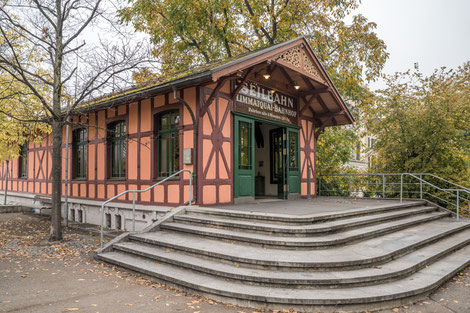 Small pink half-timbered house with lettering "Seilbahn Limmatquai-Bahnhof". There are steps in front of it.