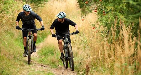 Zwei Männer auf e-Mountainbikes von Giant mit Helmen
