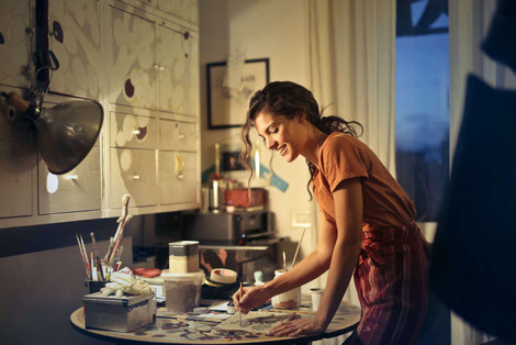 WOMAN SMILING AND PAINTNG ON A TABLE