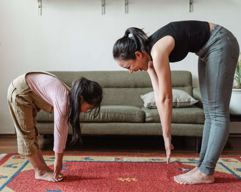 woman and a little girl touching toes and exercising at home