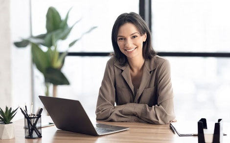 Freundliche Frau sitzt lächend vor einem Laptop