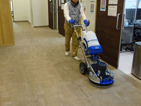 クリニック待合室のカーペットを専用洗浄機で定期清掃している施工風景