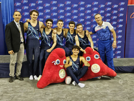 De gauche à droite : Nicolas - juge, Pierrick, Théotim, Léo, Mael, Alexian Eric l'entraineur et Ethan entouré des mascottes des JO