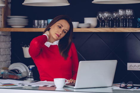 Busy professional suffering from neck and shoulder pain from sitting at her desk for many hours.