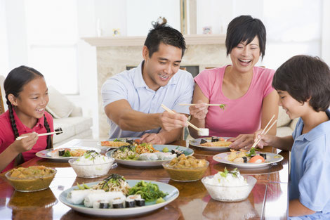 Asian family of four eating an asian meal with chopsticks