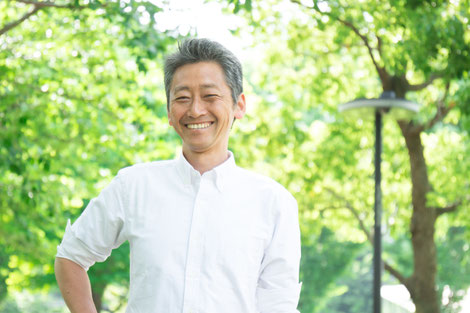 A calm and happy asian man in a white linen shirt at the park