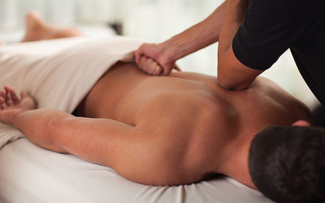 A man lying down on a massage bed while a rolfer works out the kinks in the body