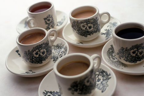 Coffee and tea served in traditional Singaporean cups on a white table