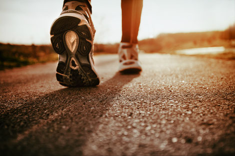 A man in his tracking shoes walking on concrete pavement