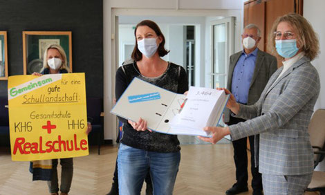 Dr. Regina Lenz überreicht Bürgermeisterin Sandra Pietschmann den Aktenordner mit den 3464 Unterschriften zum Bürgerbegehren Erhalt der Realschule. (Foto: Kreisstadt Mettmann)