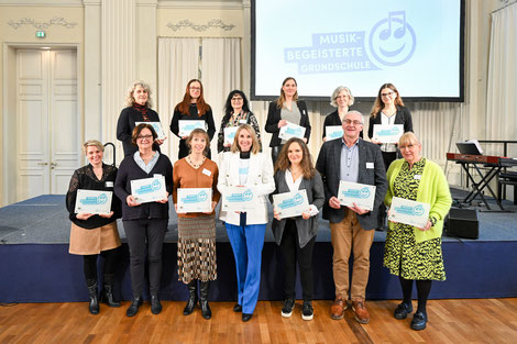 Aus Oberfranken wurden 13 Schule als „Musikbegeisterte Grundschule“ ausgezeichnet. Klemens Löffler, Rektor der Arnika-Grundschule Teuschnitz (vorne, 3. v.r.) konnte aus den Händen von Kultusministerin Anna Stolz das Profilschild entgegen nehmen.