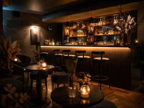 Gemütliche kleine Bar-Location mit warmem Licht, Theke und Sitzbereichen für private Feiern und Geburtstage