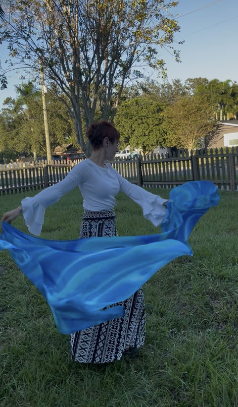 Woman holding a dance silk painted to look like blue water.
