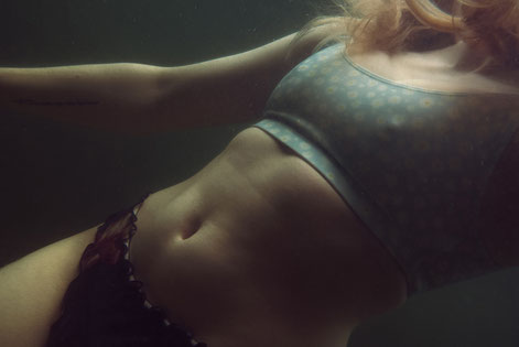 Melancholische Unterwasseraufnahme einer jungen Frau im Bikini, deren Haare sich im Wasser bewegen