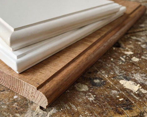 Holzfensterbänke aus unterschiedlichem Holz und mit diversen Profilen liegen auf der Hobelbank in der Tischlerei