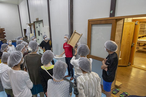 麹室の前で麹蓋を使用した麹造りの説明中。　※ 麹造りについては、「泉橋酒造の冬」特集内で紹介しています。