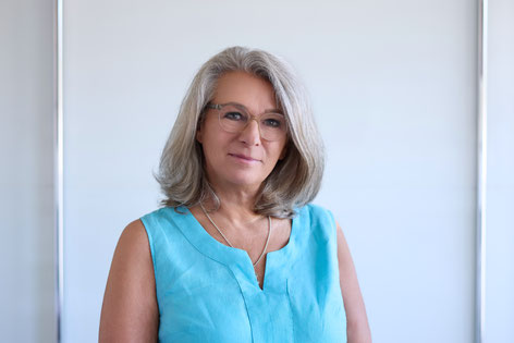 Suzann Scheidegger - Frau um die 60 Jahre graue Haare und Brille in einem türkisfarbenden Top