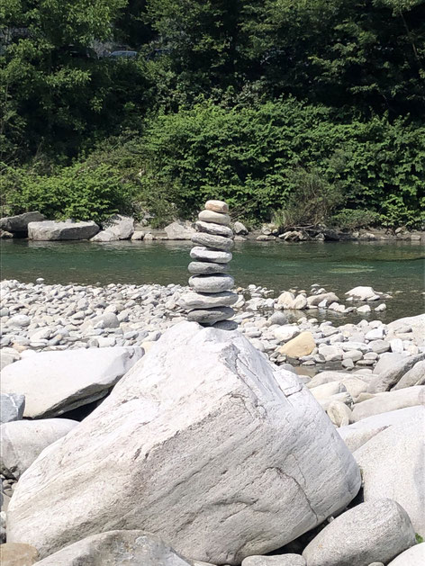 Steinmandli - aufgeschichtete Steine mit einem ruhigen Fluss im Hintergrund